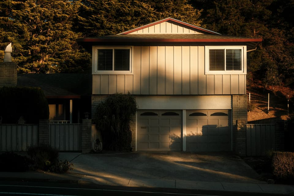 Two single-bay sectional garage doors side by side under a split-level house