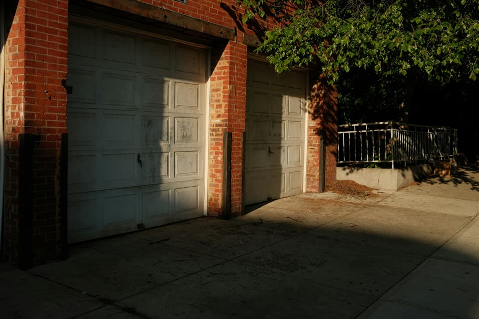 Two weathered white raised-panel garage doors set in a brick wall